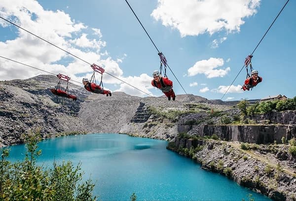 Four people zip-lining over Penrhyn Quarry at Zip World in North Wales