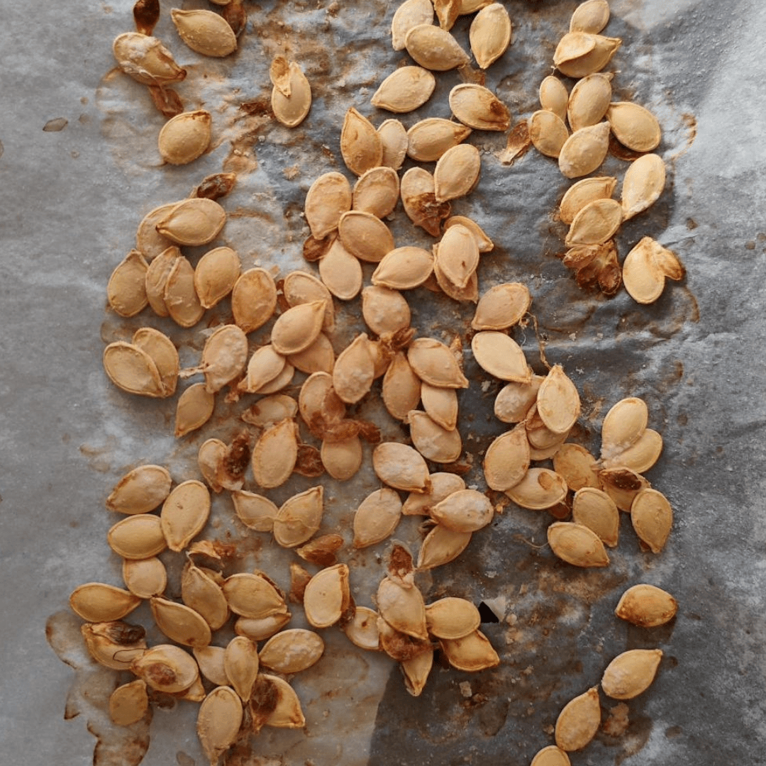 A baking tray full of roasted pumpkin seeds.