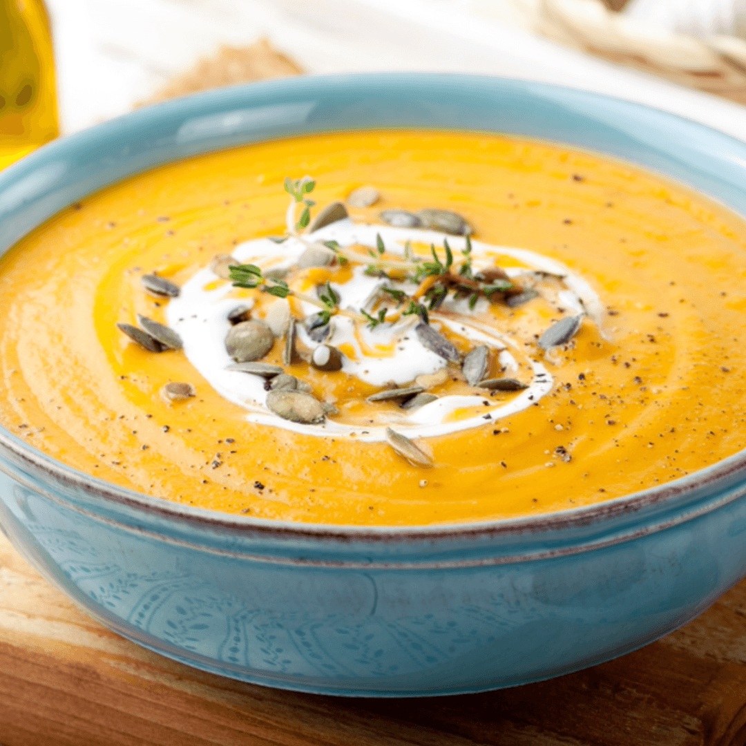 A bowl of creamy pumpkin soup topped with pumpkin seeds.