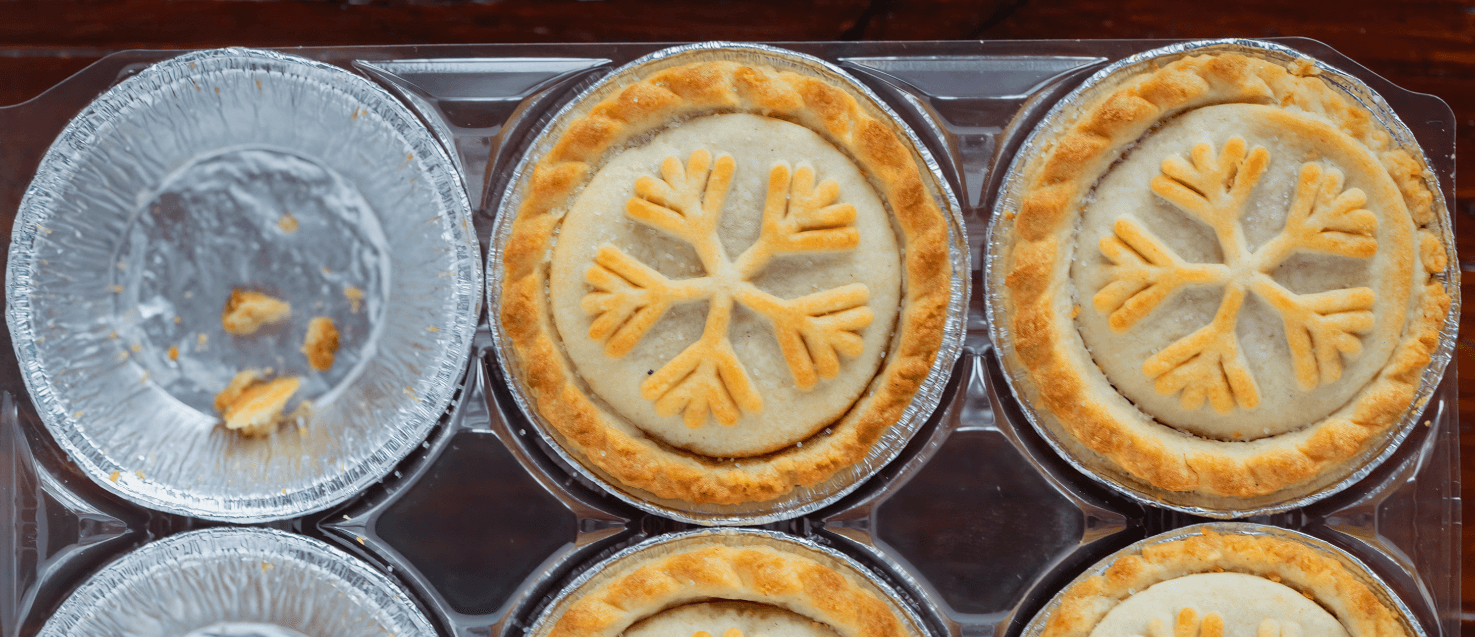 3 mince pies cases in a row. one is empty showing foil