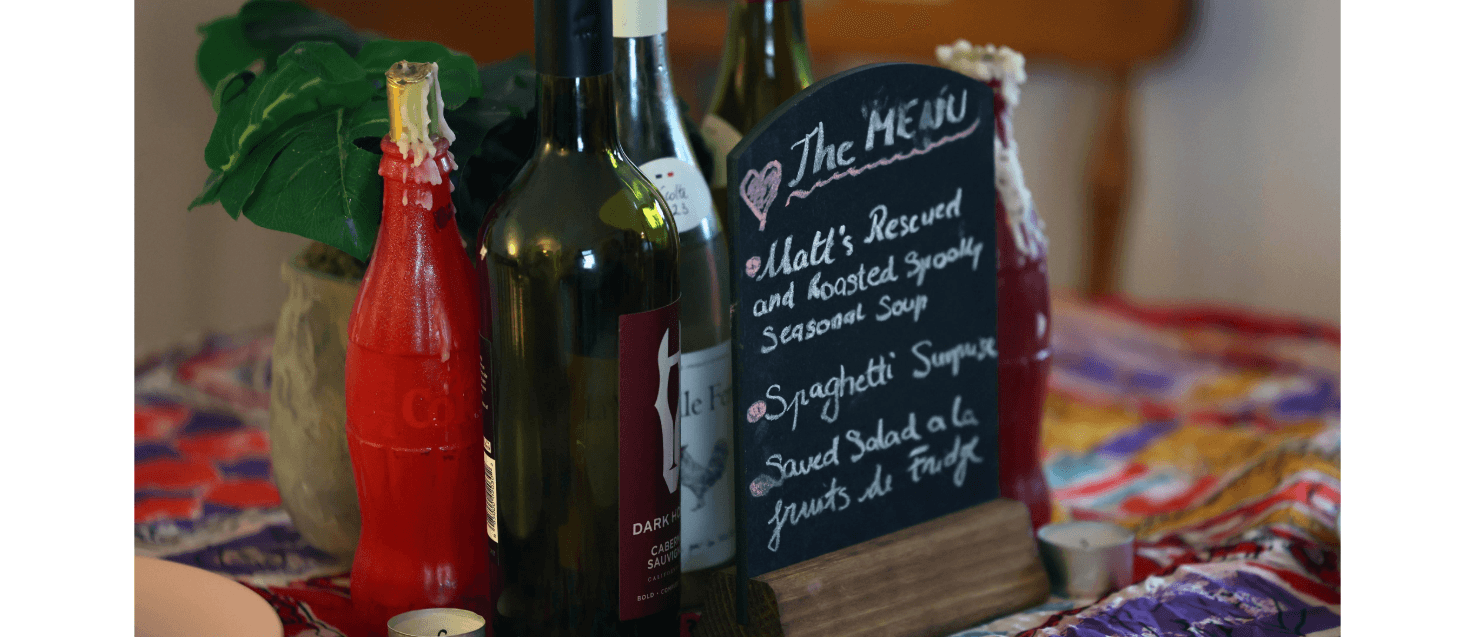 A small chalkboard menu with three courses written on it on a table with condiments