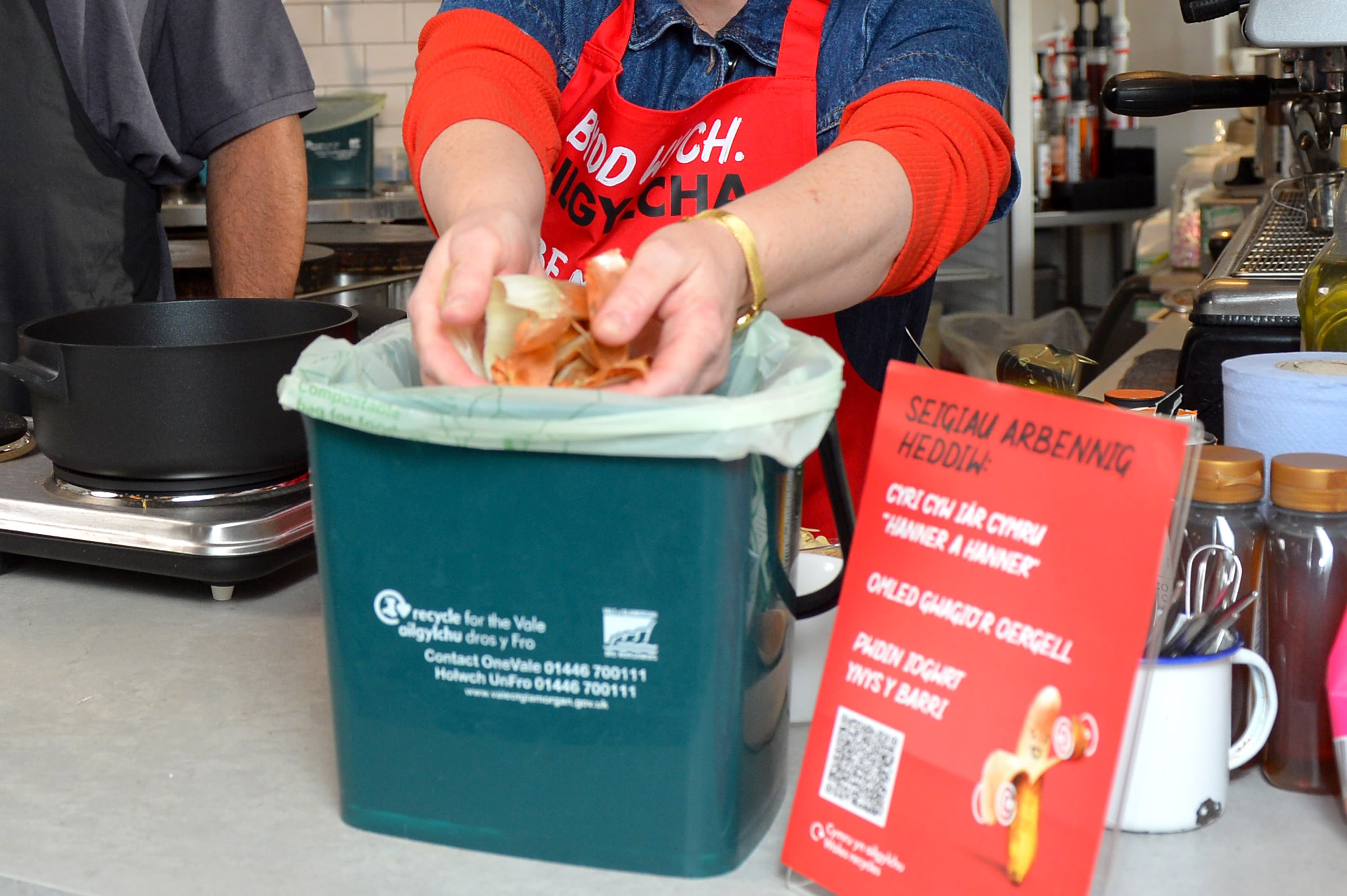 Hands dropping food waste into a kitchen caddy