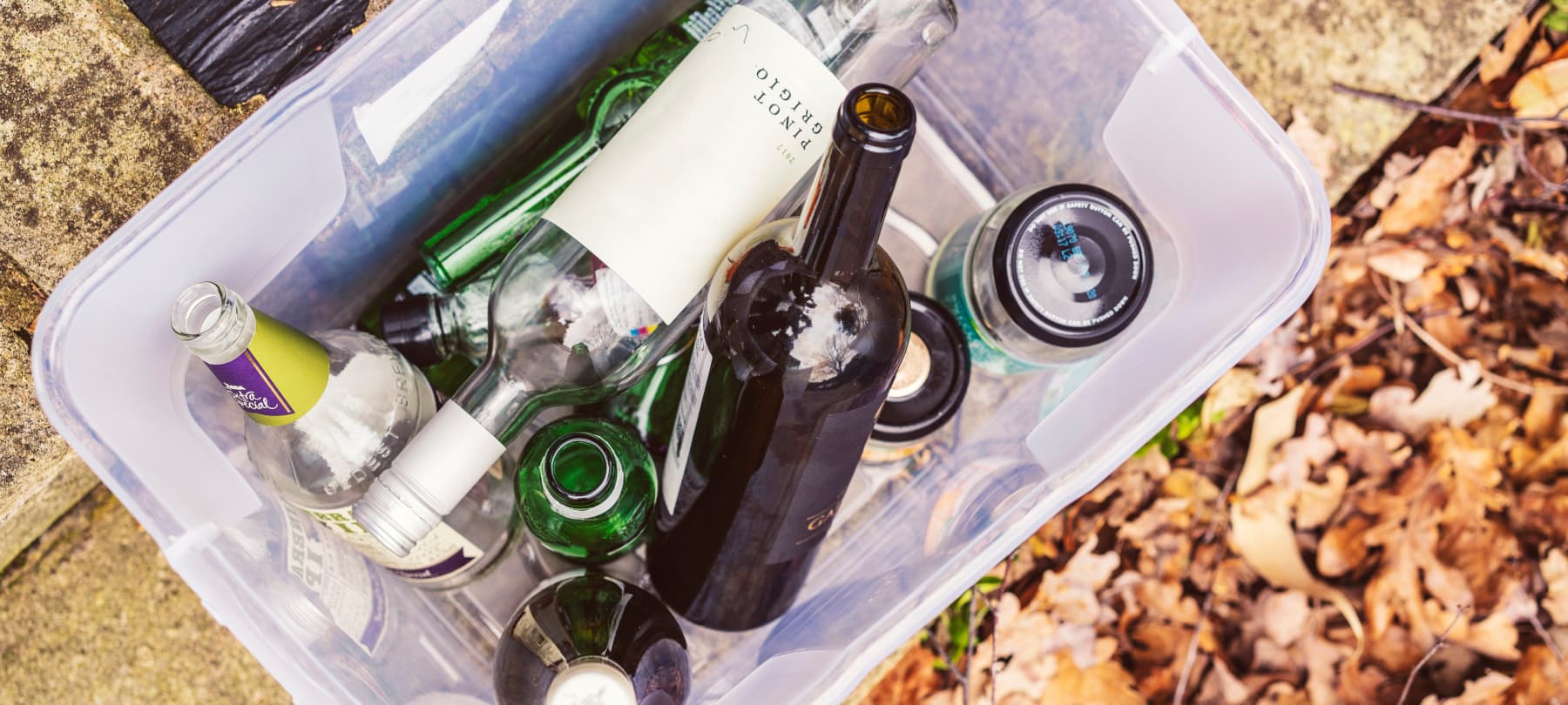 View from above of a plastic box of plastic box of glass bottles and jars to be recycled